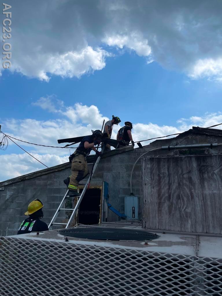 Firefighter Fries secures the ladder to assist the roof crew